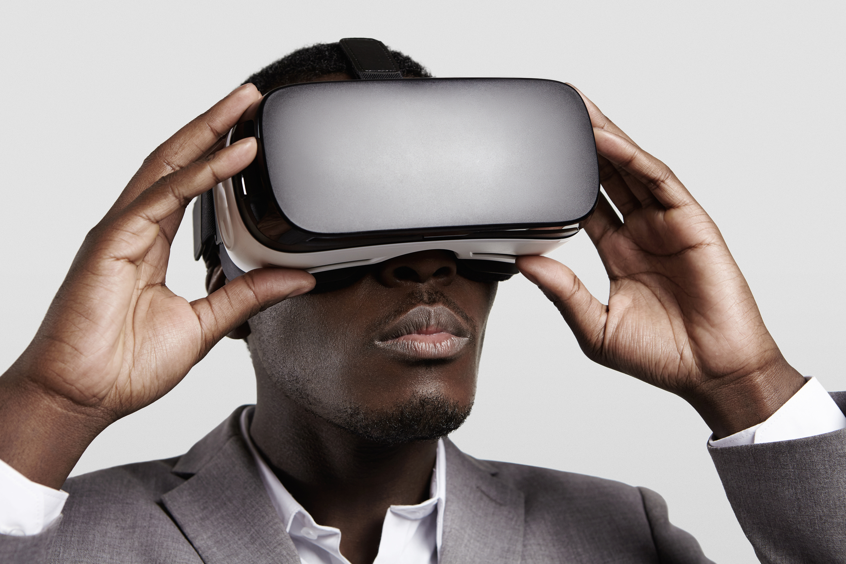 3d technology virtual reality entertainment cyberspace concept. Young dark-skinned entrepreneur wearing formal suit using oculus rift headset with head-mounted display playing video game in office