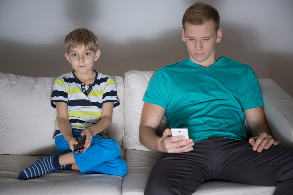bigstock-child-watching-tv-and-dad-usin-90103367