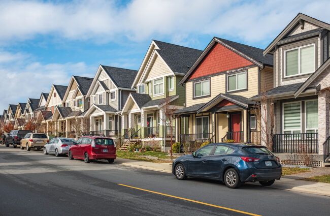 Modern residential houses neighborhood street with green plants in a suburban residential area. New and comfortable neighborhood. Townhouses on street