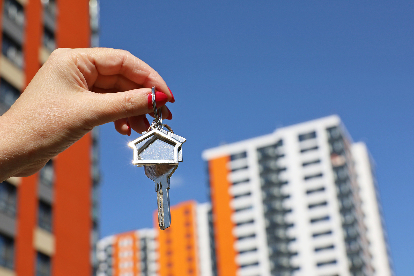 Real Estate Agent, Home Keys In Female Hand On Background Of New