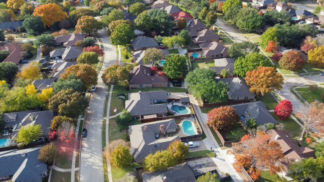 Upscale single family home with swimming pool and colorful fall foliage near Dallas, Texas, America. Aerial view an established suburban residential neighborhood in a great school district with bright autumn leaves, large street