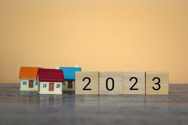 Wooden blocks with the number 2023 and house. Forecast of real estate prices, trends, and changes, new challenges for the economy, and the impact on the housing market.