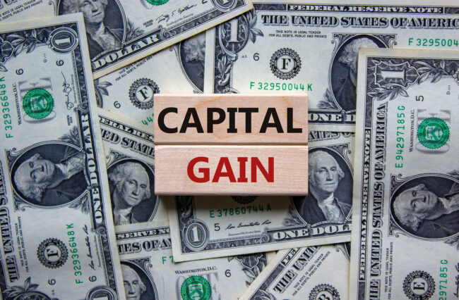 Capital gain symbol. Concept words 'Capital gain' on wooden blocks on a beautiful background from dollar bills. Business and capital gain concept.